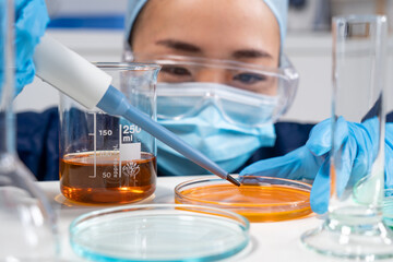 Femme asiatique dans un laboratoire de recherche médicale avec pipette.