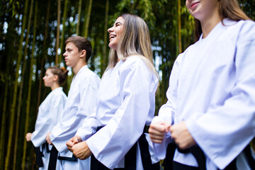 people high kicks during training of taekwondo outdoors bamboo background