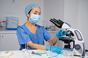 Femme asiatique dans un laboratoire de recherche médicale avec microscope.