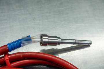  broken red fiber optic cable lies on a silver base