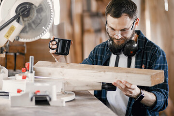 Wood cutting with circular saw. Closeup of mature man sawing lumber.