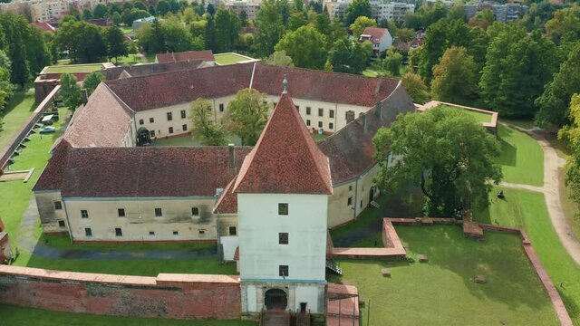 Sarvar, Hungary - 4K drone flying away backwards the famous Castle of Sarvar (Nadasdy castle) on a sunny summer day with green trees and blue sky. The town of Sarvar has been located in Vas county