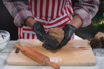 Male model in red striped apron preparing cookies, showing gingerbread dough in hand, making Christmas cookies concept