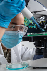 Gros plan sur les yeux d'une femme asiatique chercheur avec pipette et microscope.