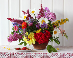 bouquet of different garden flowers in a clay jug.