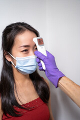 Mesure de température supérieure à 37 degrés celsius au front d'une jeune femme asiatique.