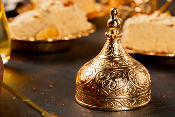 Golden cap for turkish cup on dark surface with halva pastries