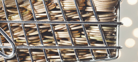 Close up picture of golden coins in a miniature shopping cart, color toned conceptual picture, selective focus.