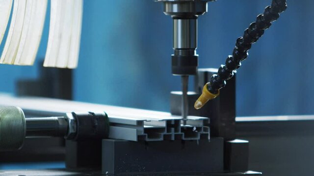 Worker operating automatically drilling drill which drills holes in a metal profile