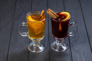 Two glasses of red and white mulled wine on black wooden background