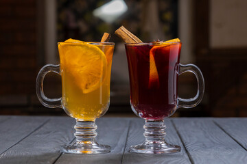 Two glasses of red and white mulled wine on black wooden background