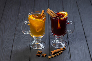 Two glasses of red and white mulled wine on black wooden background