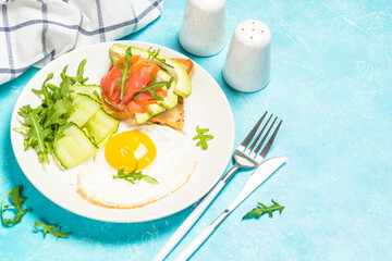Breakfast. Fried egg, toast with salmon and avocado and fresh salad.