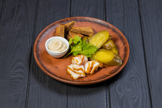 Ukrainian traditional appetizer of bacon, pickled cucumbers and bread on a black wooden background