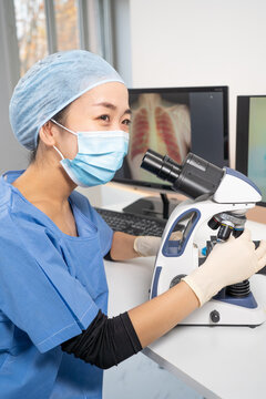 Femme m&eacute;decin asiatique regarde au microscope des images m&eacute;dicales du covid-19 et de scanner des poumons infect&eacute;s.