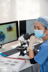 Femme médecin asiatique regarde au microscope des images médicales du covid-19 et de scanner des...