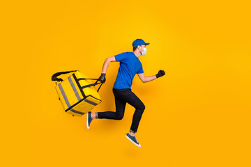 Fototapeta na wymiar Full size profile photo of running deliveryman wear medical safety mask gloves isolated on yellow color background