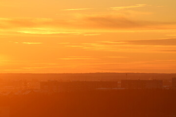 Sun below the horizon and clouds in the fiery dramatic orange sky at sunset or dawn backlit by the sun. Place for text and design