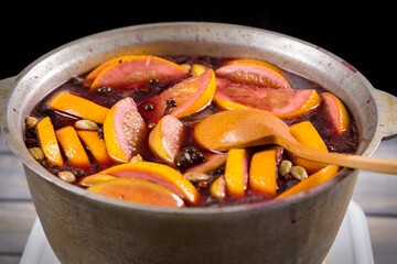 Wooden spoon in mulled wine prepared in metal kettle