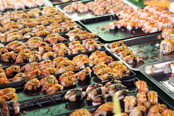 Assorted Sushi seafood line up on a table tray at the walking street market in Thailand Local food market, Cheap food