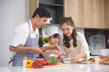 Asian family enjoy with cooking together salad foods homemade in kitchen room at modern home. Create activities together in the family. Focusing on center girl children.