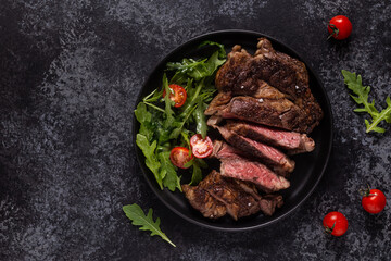Grilled beef steak with spices on a black plate