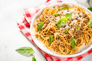 Pasta Bolognese, meat ragout in tomato sause in white plate at stone table. traditional italian cuisine.