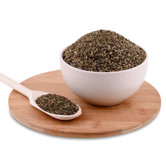 Pile of dried basil spice in white ceramic bowl on wood board isolated on white background, copy space.