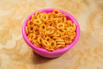 Baked round sushki sprinkled with salt in a purple plastic bowl. Traditional snack in Russia
