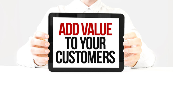 Text ADD VALUE TO YOUR CUSTOMERS on tablet display in businessman hands on the white bakcground. Business concept