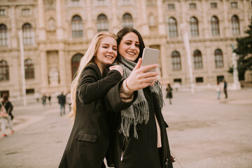 Young female tourists taking selfie with mobile photo in centre of Vienna, Austria