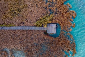 Balatonfuzfo, Hungary - Aerial top down view of beautiful reeds formation with pier and crystal clear blue water at lake Balaton