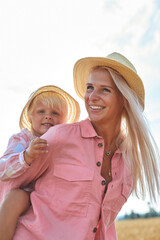 happy mother holding baby smiling on a wheat field in sunlight