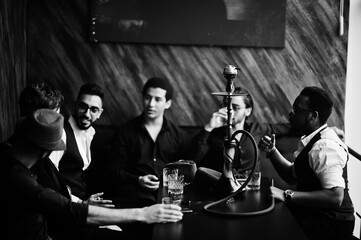 Group of handsome retro well-dressed man gangsters spend time at club, smoking hookah. Multiethnic male bachelor mafia party in restaurant.