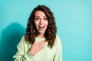 Fototapeta premium Photo of amazed beautiful lady dressed casualwear green pullover hold arm on breast isolated on turquoise color background