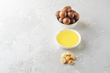 Bowl with macadamia oil on a grey concrete background with a copy of space.