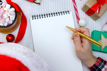 child in red hat writes letter to Santa and next to marshmallow and candy cane. selective focus 