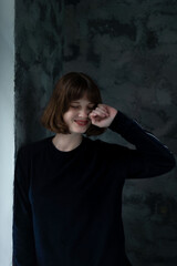 portrait of a young beautiful young girl twenty-three years old, smiling, against a dark wall