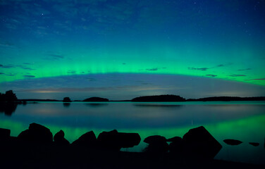 Northern lights dancing over calm lake. Farnebofjarden national park in north of Sweden.