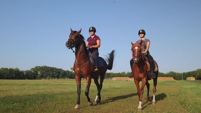 riding horses at paddock of farm, two women are training
