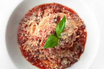 Italian Cuisine Pasta Bolognese With Basil Leaf On Top Closeup. Spaghetti With Meat Traditional Dinner Background. Macaroni With Red Tomato Sauce And Cheese.