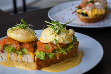 Plates and fresh toasts with salmon, guacamole, poached egg, with sauce. Fresh food close-up