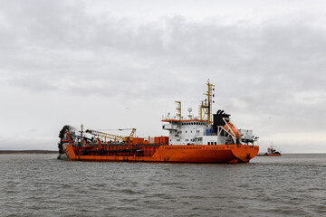 Fototapeta premium Vessel engaged in dredging. Dredger working at sea. Ship excavating material from a water environment.