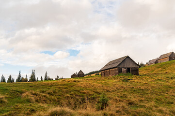 Obraz premium Old wooden houses in the highlands. Bottom view of the houses. Clouds over houses in the mountains.