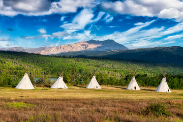 Beautiful View of the Tipi in a field with American Rocky Mountain Landscape in the background. Colorful Sunny Morning Sky. Taken in Montana near Glacier National Park, USA. © edb3_16