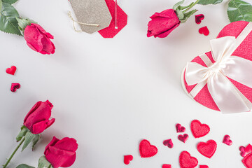 Valentine's Day background. Flat lay frame made with rose flowers, gifts, candles, confetti on white background. Valentines day greeting card concept. Top view, copy space.