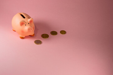 Close-Up Of Piggy Bank With Coins Against Pink Background