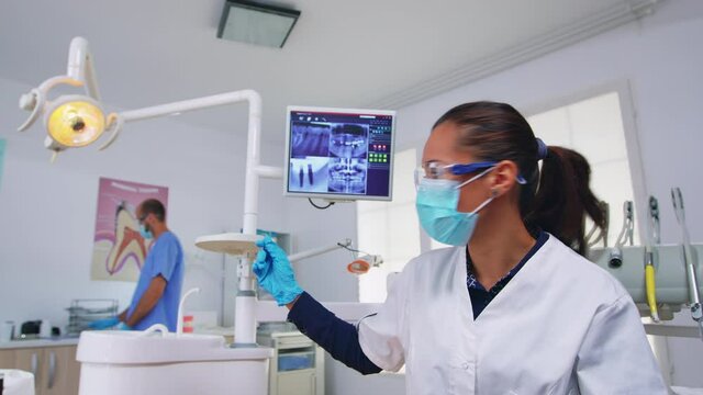 Patient pov looking at dentist asking for dental x-ray showing teeth image. Stomatology specialist wearing protective mask, working in modern stomatological clinic, explaining radiography of tooth