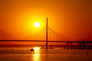 sunset over the cable-stayed bridge reflecting in the river water