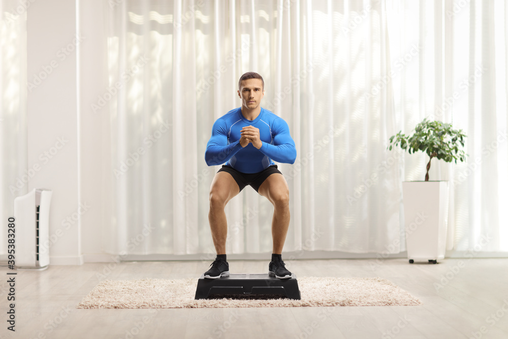 Sticker Fit muscular young man doing squat exercise on a step aerobic platform